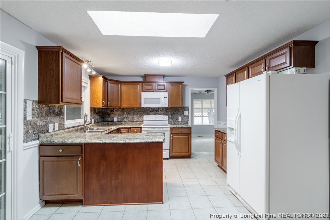 1412 Milton Street Spring Lake, NC 28390 - Photo 11 of 27 a kitchen with granite countertop a refrigerator a sink a stove top oven and cabinetry