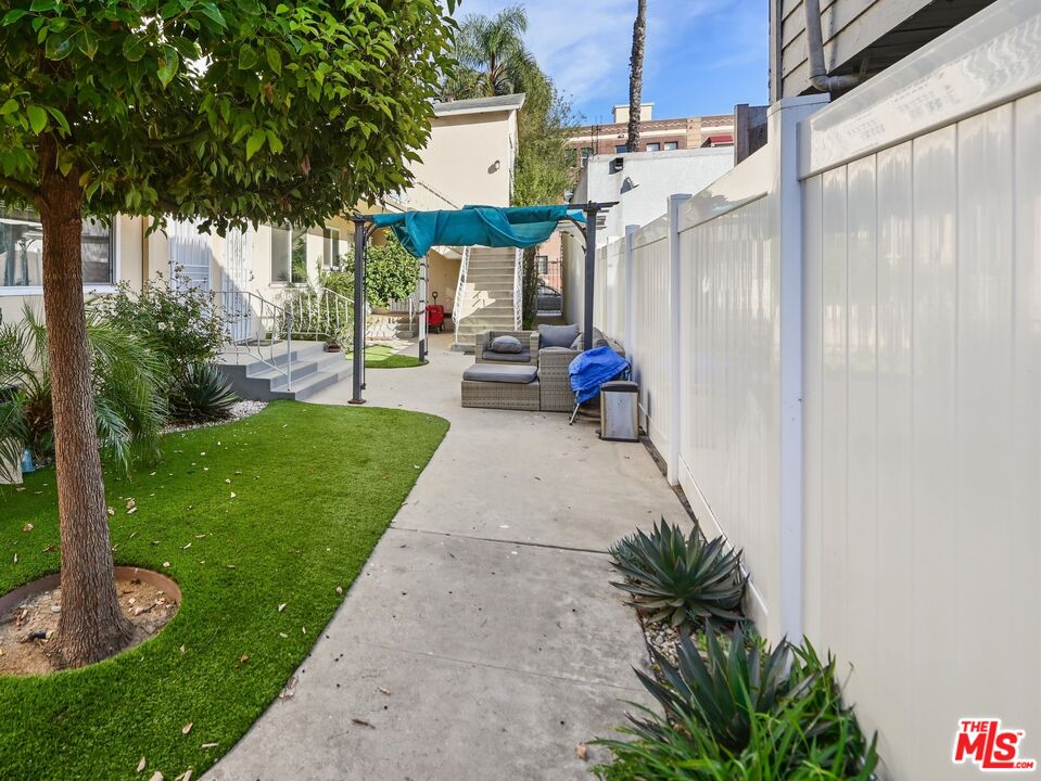 815 Pacific Avenue, Unit 9 Long Beach, CA 90813 - Photo 21 of 25 a view of a patio with table and chairs potted plants and a large tree