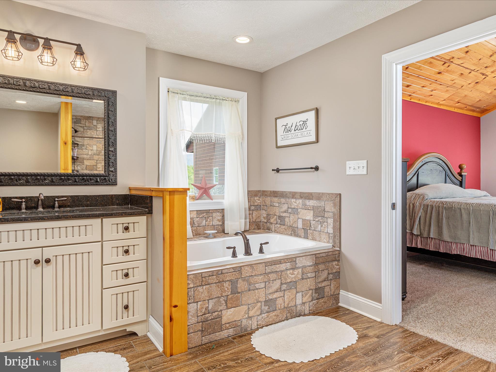 1996 Buck Mountain Road Bentonville, VA 22610 - Photo 27 of 61 a bathroom with a granite countertop sink a mirror and a bathtub