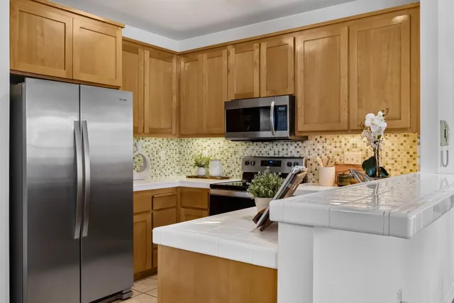a kitchen with stainless steel appliances a microwave sink refrigerator and cabinets