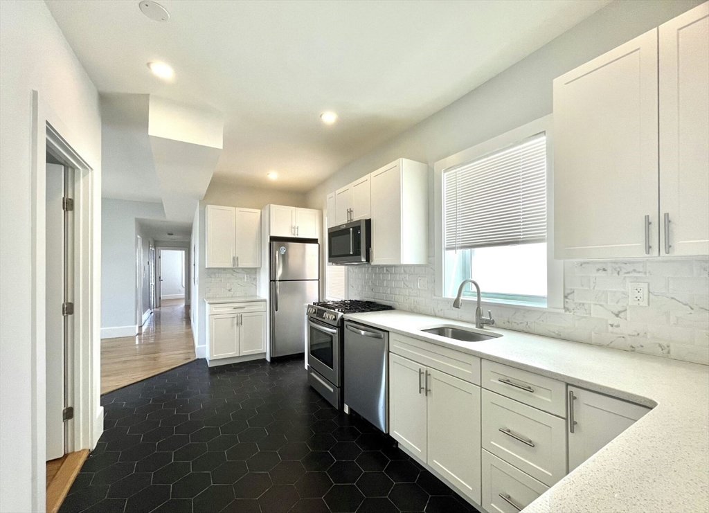 301 Hancock Street, Unit 2 Boston, MA 02125 - Photo 2 of 11 a kitchen with a sink cabinets stainless steel appliances and a window