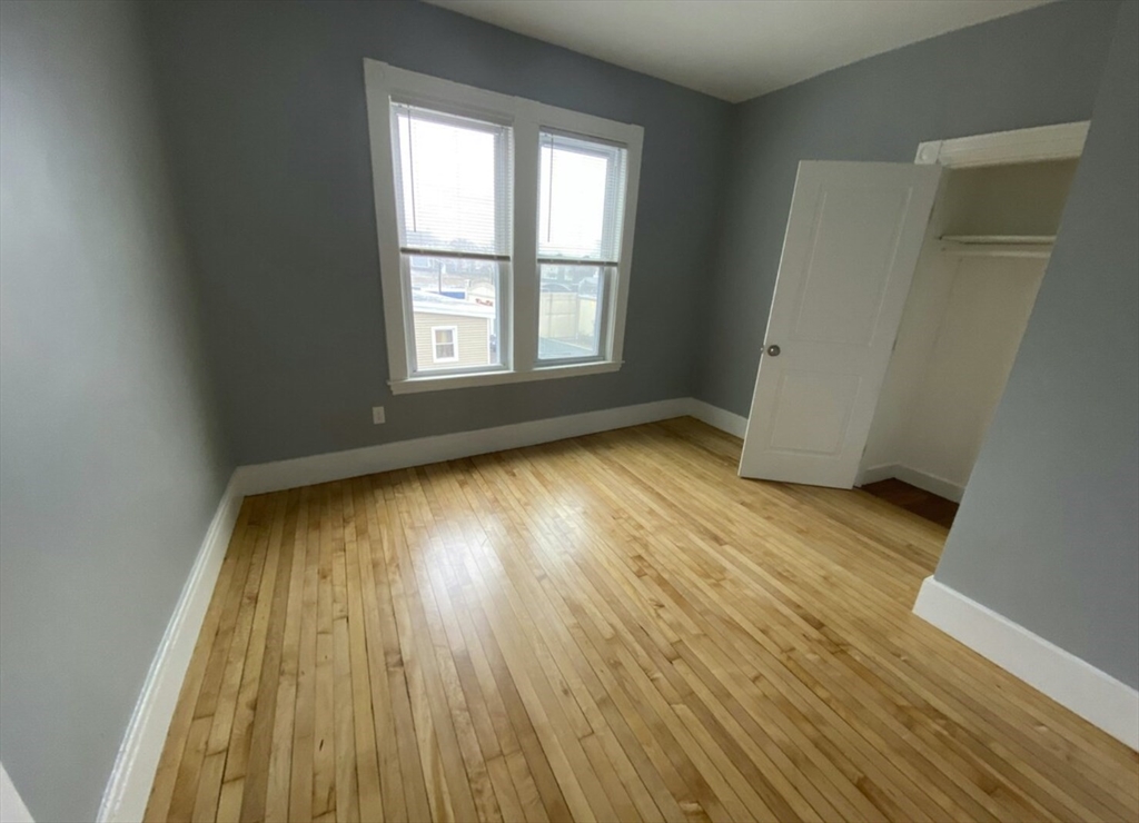 301 Hancock Street, Unit 2 Boston, MA 02125 - Photo 3 of 11 an empty room with wooden floor and windows