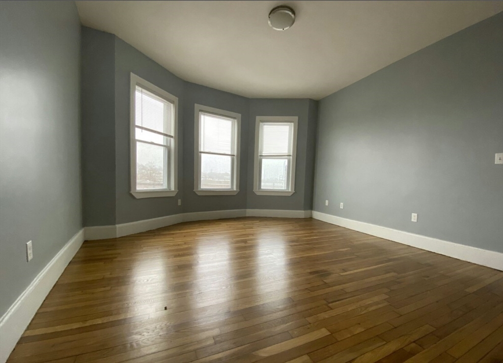 301 Hancock Street, Unit 2 Boston, MA 02125 - Photo 5 of 11 an empty room with wooden floor and windows