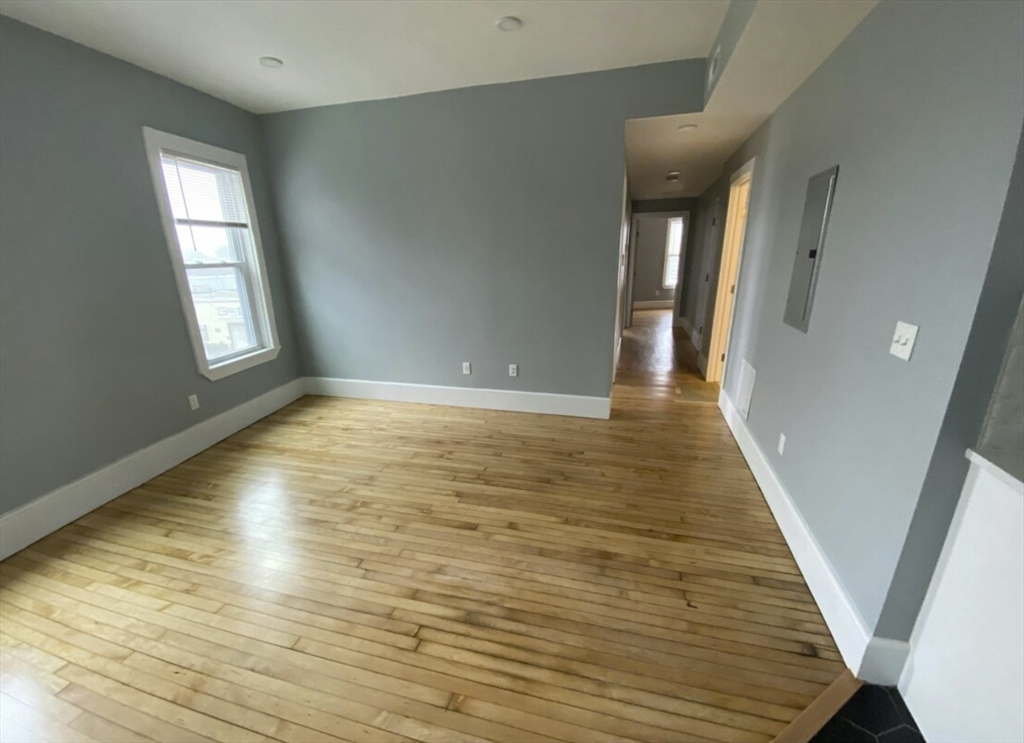 301 Hancock Street, Unit 2 Boston, MA 02125 - Photo 10 of 11 a view of an empty room with wooden floor and a window