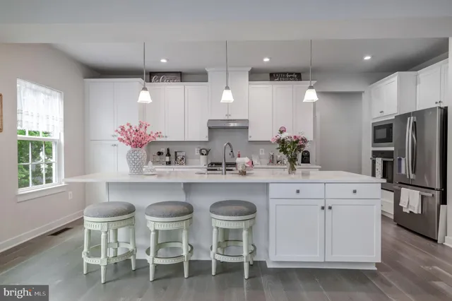 a kitchen with granite countertop a refrigerator stove and white cabinets