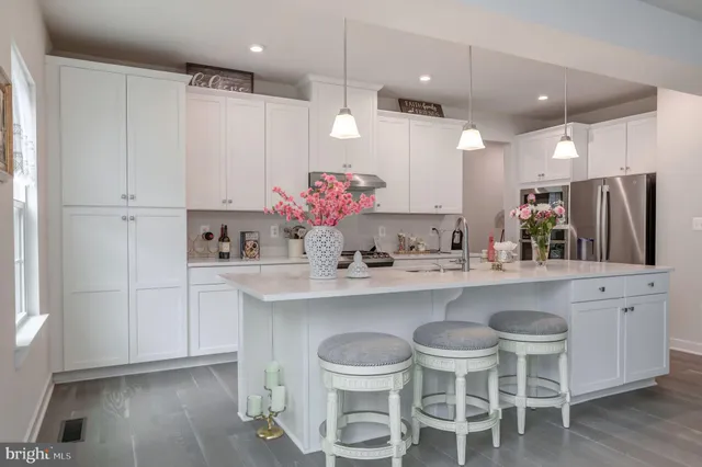 a kitchen with granite countertop a stove a sink dishwasher and white cabinets