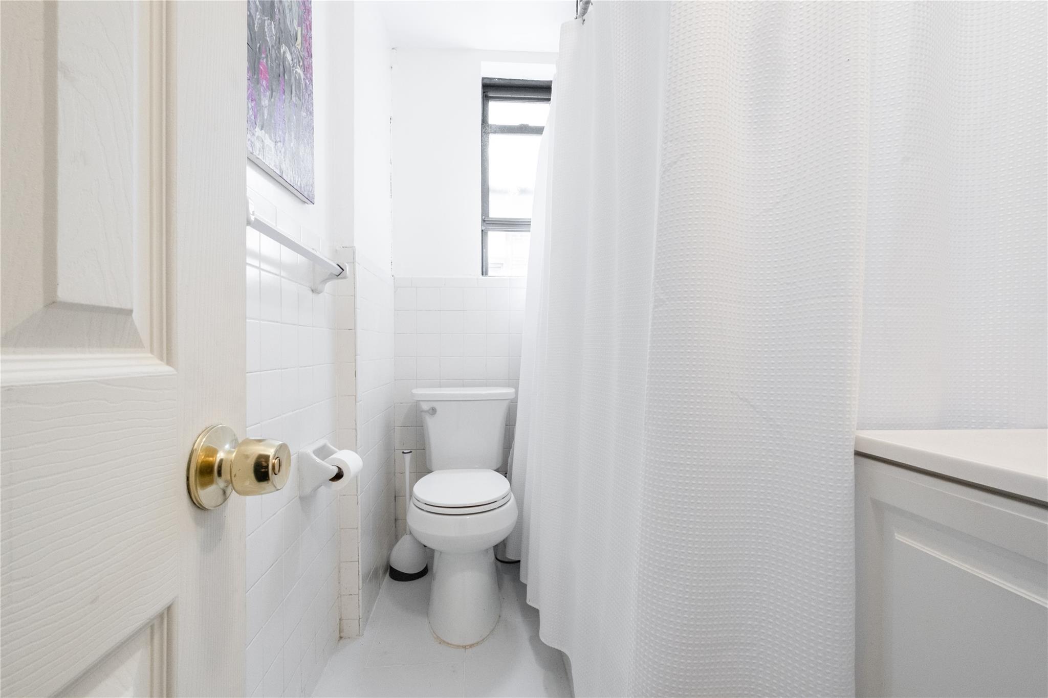 760 Brady Avenue, Unit 417 Bronx, NY 10462 - Photo 11 of 27 a white toilet sitting next to a shower curtain
