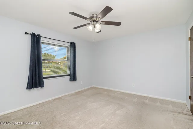 an empty room with ceiling fan and window