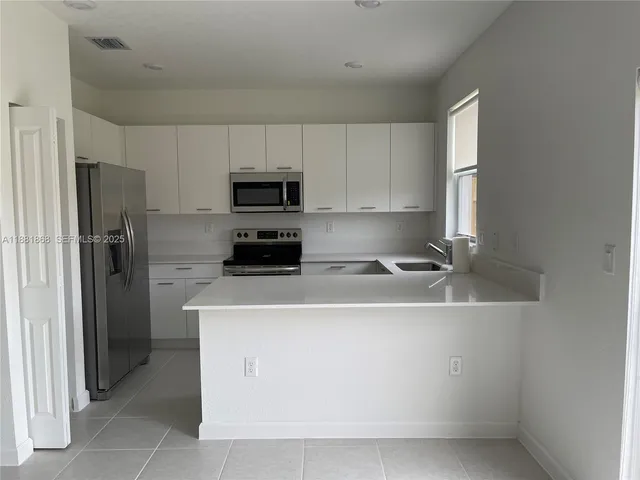 a kitchen with a sink a refrigerator and cabinets