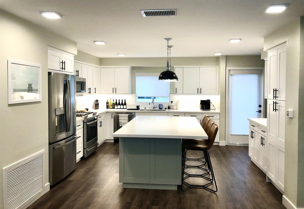 1903 South Myers Street, Unit 3 Oceanside, CA 92054 - Photo 8 of 30 a kitchen with kitchen island a refrigerator a sink dishwasher a stove and white cabinets with wooden floor