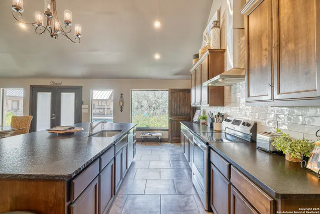 a kitchen with stainless steel appliances granite countertop a sink counter space and living room view