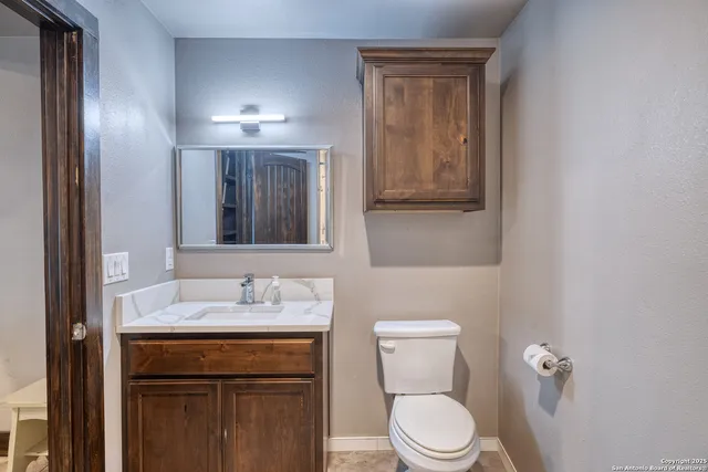 a bathroom with a granite countertop toilet sink and mirror