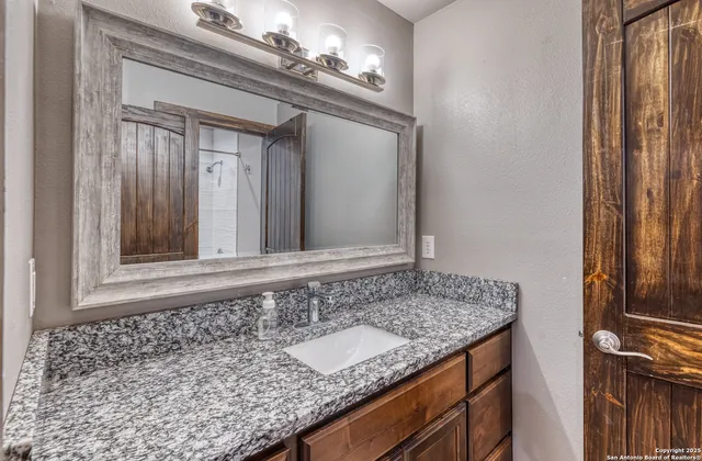 a bathroom with a granite countertop sink and a mirror