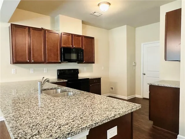 a kitchen with granite countertop wooden cabinets and stainless steel appliances