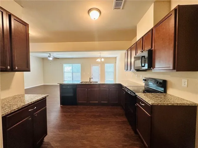 a kitchen with stainless steel appliances granite countertop a stove a sink dishwasher and a refrigerator with wooden cabinets