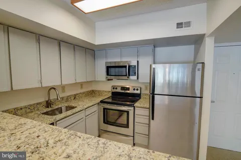 a kitchen with granite countertop a refrigerator stove and sink