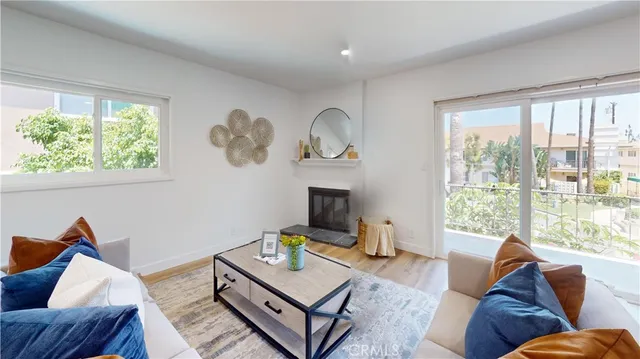 a living room with fireplace furniture wooden floor and a large window