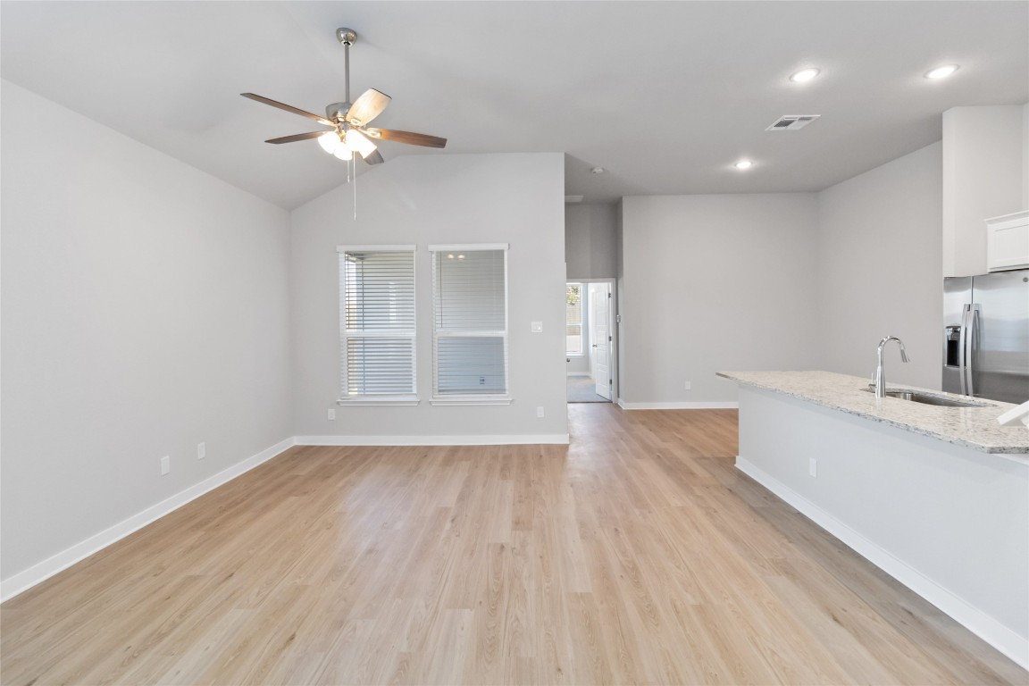 840 Staglin Street, Unit B Buda, TX 78610 - Photo 2 of 17 Unfurnished living room with light wood-style floors, ceiling fan, vaulted ceiling, and recessed lighting