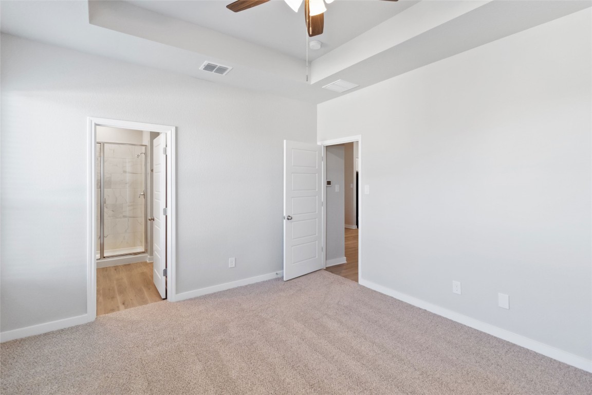 840 Staglin Street, Unit B Buda, TX 78610 - Photo 9 of 17 Unfurnished bedroom with light colored carpet, a ceiling fan, and ensuite bath