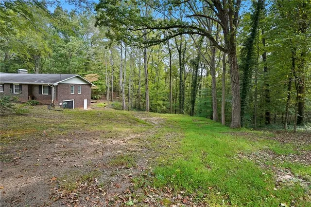 a view of a yard in front of a house with large trees