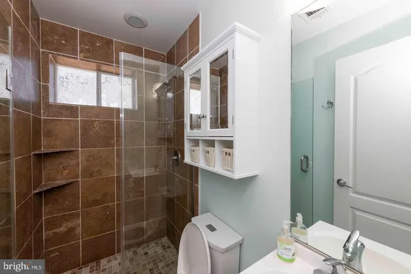 a bathroom with a toilet a sink a shower and a mirror