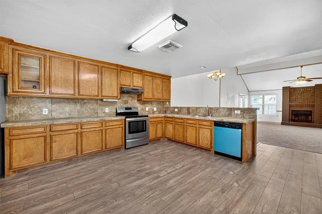 a kitchen with stainless steel appliances kitchen island granite countertop wooden floors and sink