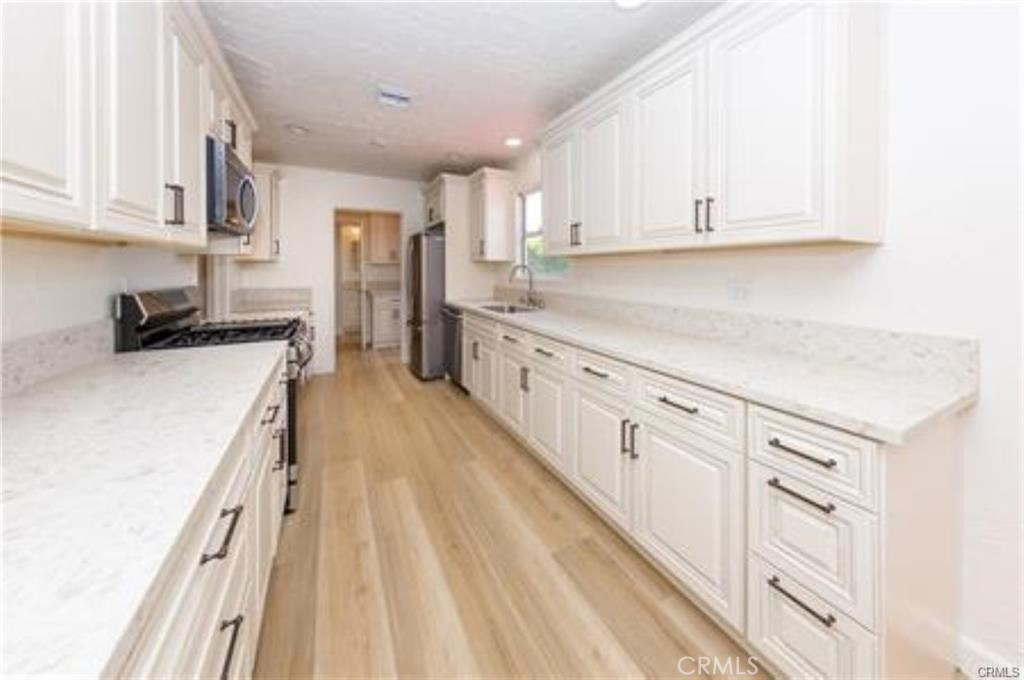 15853 Romar Street North Hills, CA 91343 - Photo 3 of 16 a kitchen with granite countertop white cabinets and white appliances