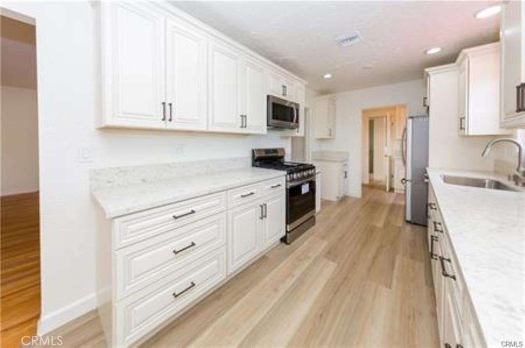 15853 Romar Street North Hills, CA 91343 - Photo 4 of 16 a kitchen with stainless steel appliances granite countertop a sink dishwasher a refrigerator and white cabinets with wooden floor