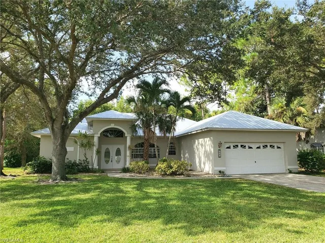 a front view of a house with a garden and trees