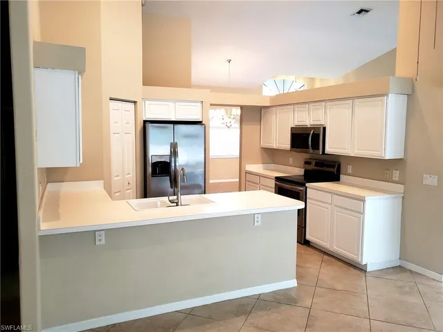 a room with kitchen island a sink stainless steel appliances and cabinets