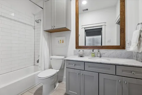 a bathroom with a granite countertop toilet sink and mirror