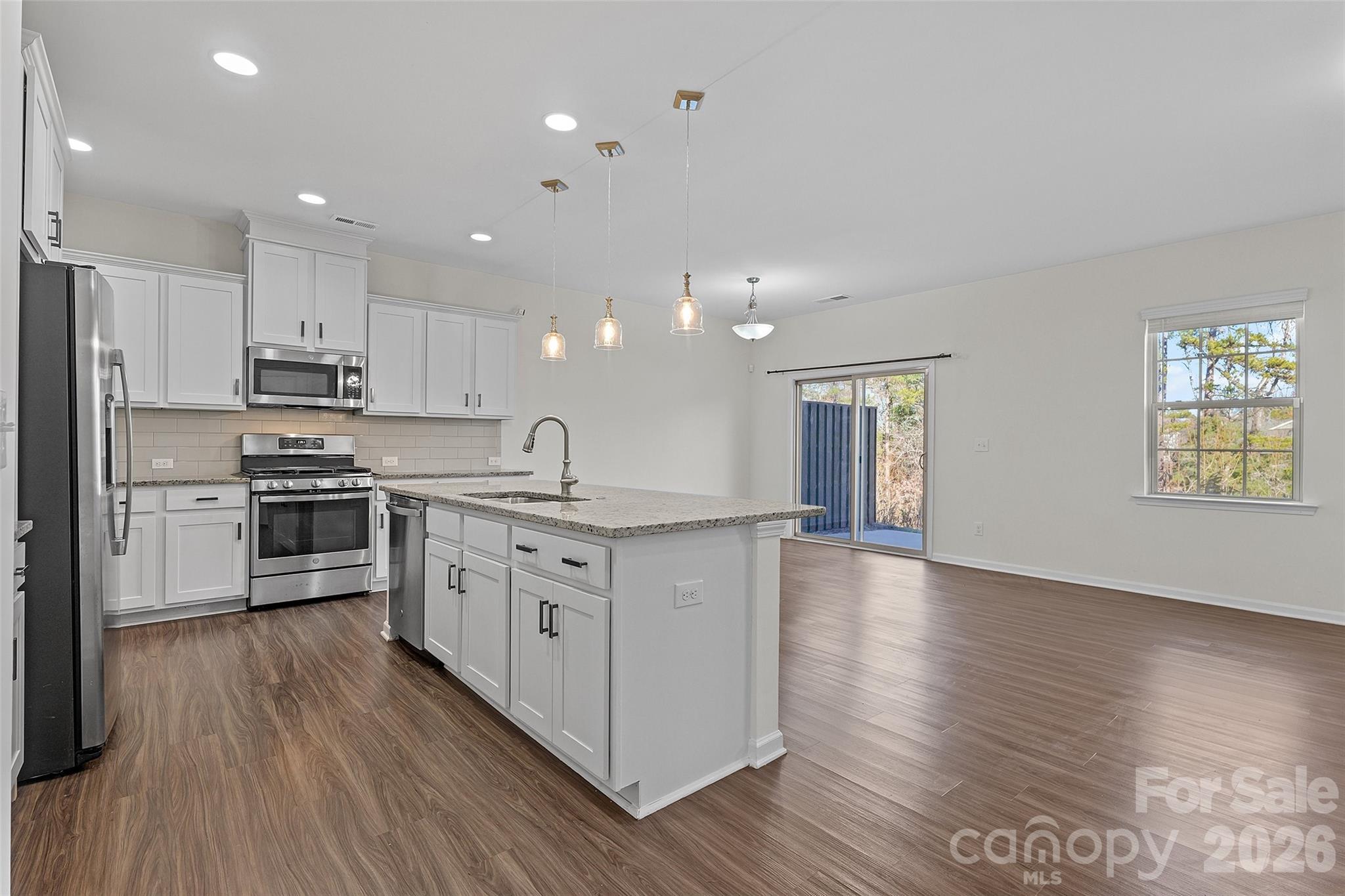 620 Amber Meadows Way Tega Cay, SC 29708 - Photo 8 of 27 a kitchen with stainless steel appliances granite countertop a stove a sink and white cabinets with wooden floor next to windows