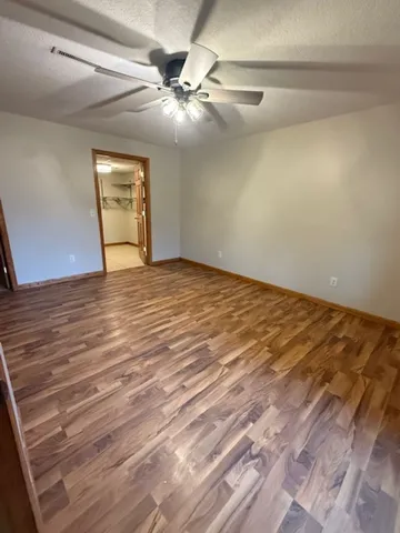 a view of a room with wooden floor and a ceiling fan