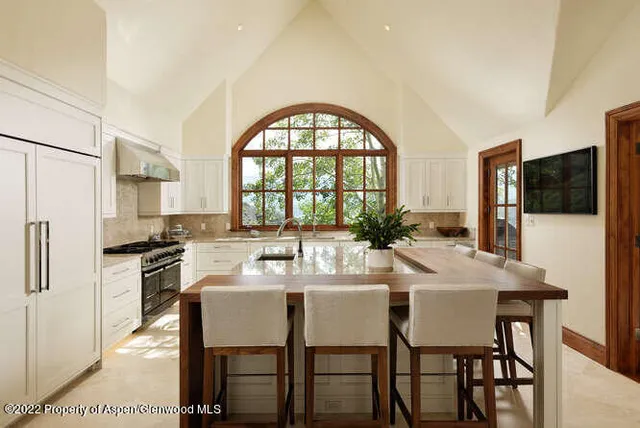 a kitchen with stainless steel appliances granite countertop a dining table and chairs