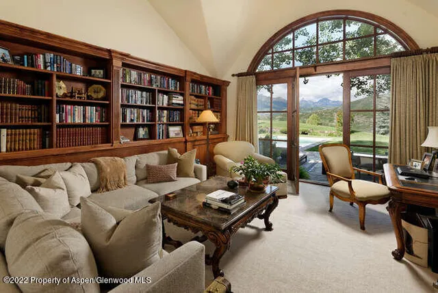 a living room with furniture a bookshelf and a large window