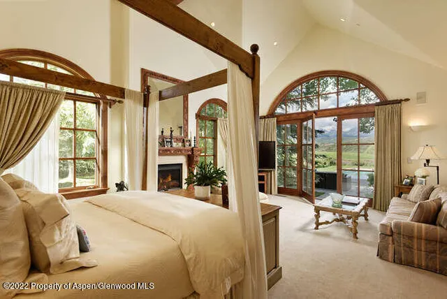 a bedroom with furniture a fireplace and a large window