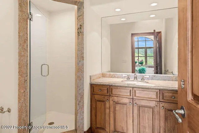 a bathroom with a granite countertop sink a mirror and a shower