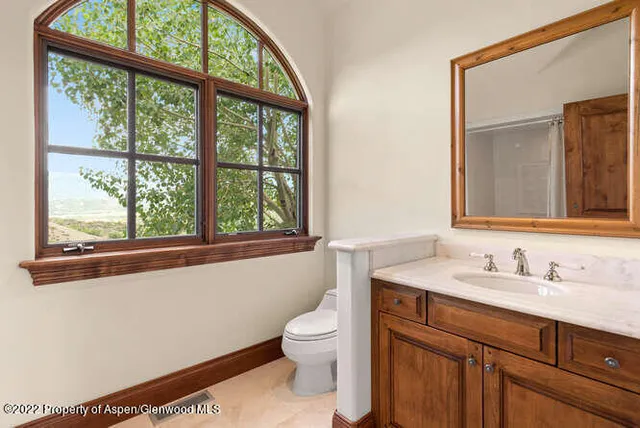 a bathroom with a toilet a sink a mirror and a window