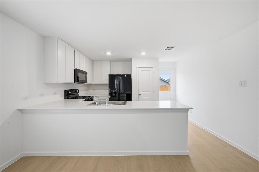 1034 Raintree Road Princeton, TX 75407 - Photo 5 of 21 a kitchen with stainless steel appliances a sink a stove a microwave a sink a refrigerator and cabinets