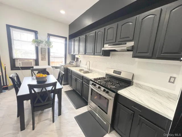 a kitchen with granite countertop a stove a sink dishwasher a dining table and chairs with wooden cabinets