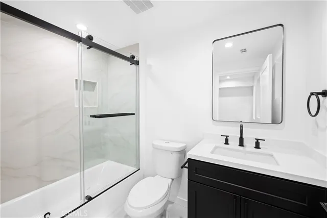 a bathroom with a shower sink vanity mirror and toilet