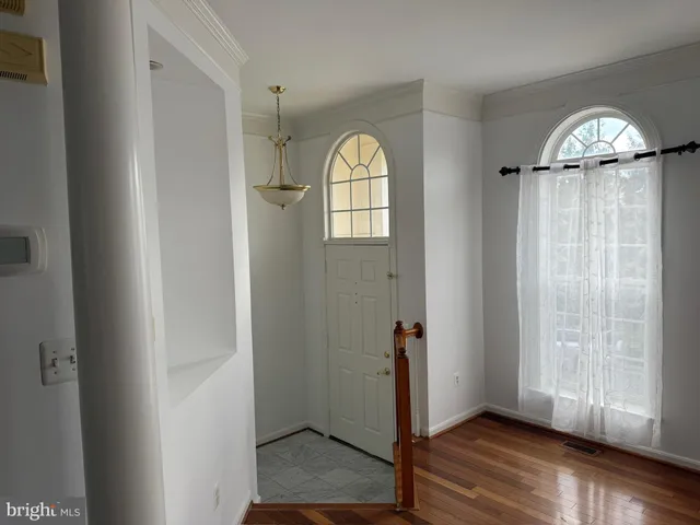 an empty room with wooden floor closet and windows