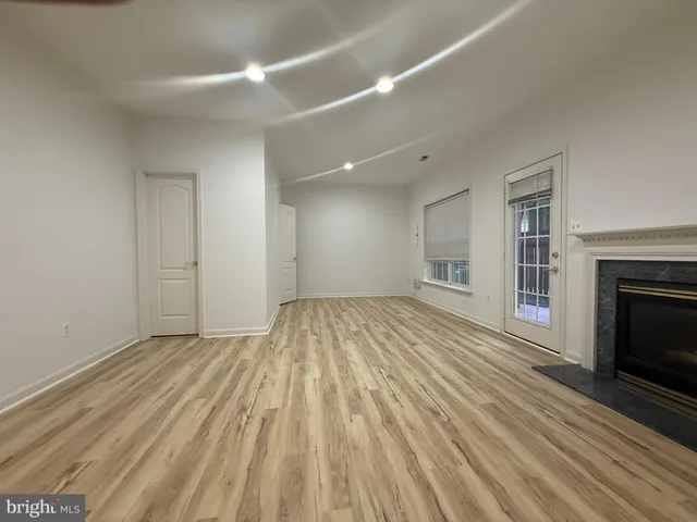 a view of empty room with wooden floor and fireplace