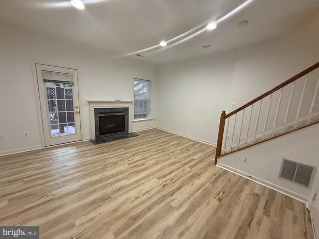 a view of an empty room with wooden floor fireplace and a window