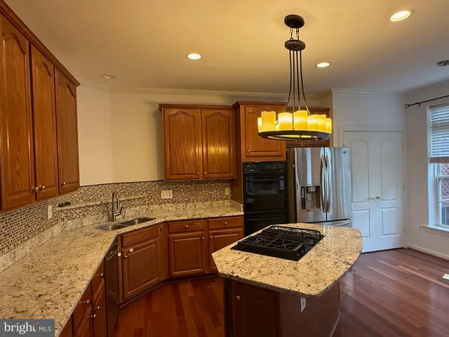 a kitchen with kitchen island granite countertop a sink a counter top space and cabinets
