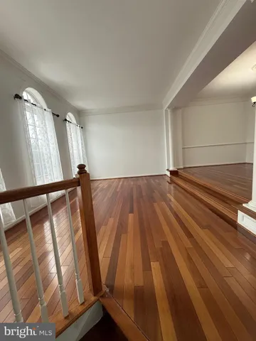 a view of an empty room with wooden floor and stairs