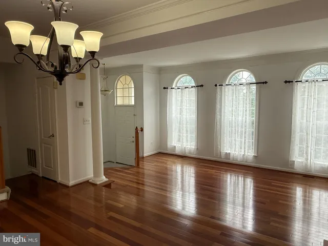 a view of a room with wooden floor chandelier and windows