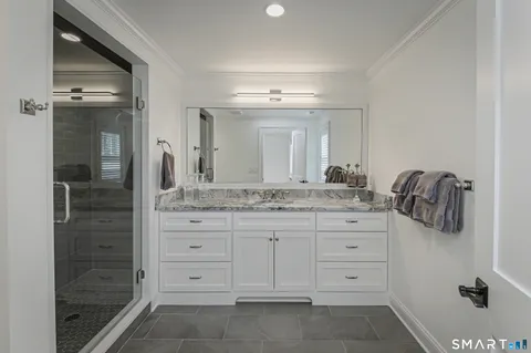 a bathroom with a granite countertop shower a mirror and sink