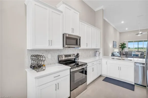 a kitchen with stainless steel appliances granite countertop a stove a sink and white cabinets