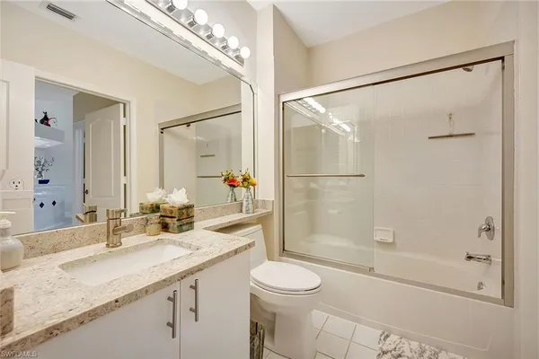 a bathroom with a granite countertop sink a toilet and shower